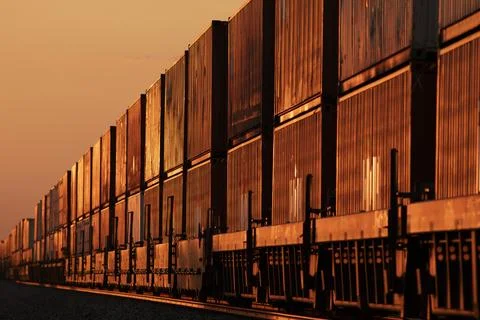 A long container stack train glowing in the amber sunset Stock Photos
