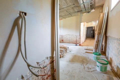 Long corridor and room with construction materials, cable trays and walls with Stock Photos