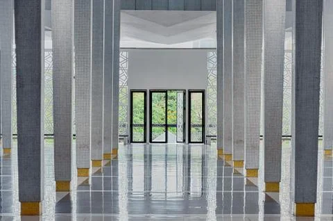 Long corridor between many columns, open doors in the end Stock Photos