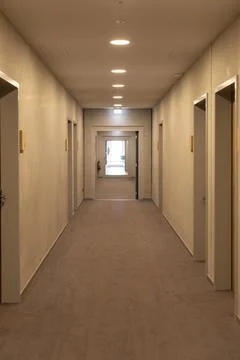 A long corridor features beige walls and carpeting, with doors on either si.. Stock Photos
