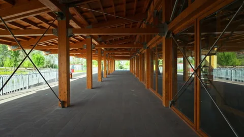 A long, covered outdoor walkway features a series of sturdy wooden support... Stock Footage 339307855