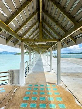 Long Covered Pier Extends Over Turquoise Sea Under Summer Sky Stock Photos