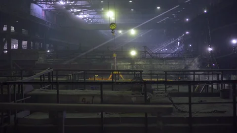 In the long dark workshop workers operate a yellow loading mechanism Stock Footage 115928850