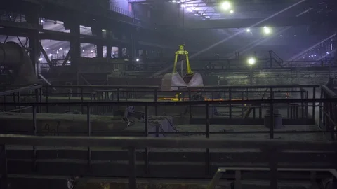 In the long dark workshop workers operate a yellow loading mechanism Stock Footage 115928999