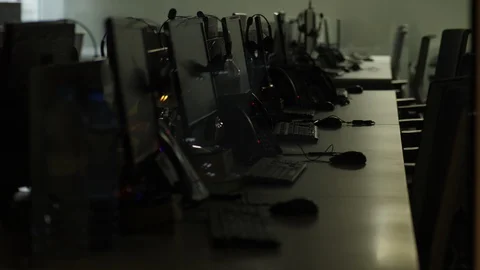 Long desk with many computer monitors and keyboards, dark room at office Video stock 99047036