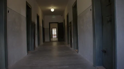 A long dimly lit corridor with rows of metal doors on both sides 스톡 동영상 299047753