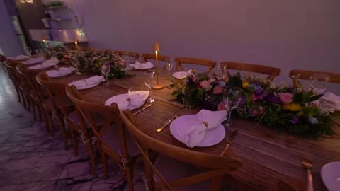 Long dinner table set for an event under a hanging greenery ceiling Stock Footage 345550301
