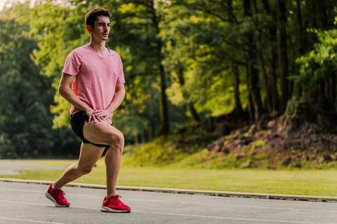 Long-distance runner doing leg stretches on the athletics track. Copy space Stock Photos