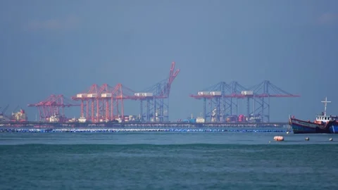 Long-distance view of a large crane at a port loading cargo onto a ship,  Stock Footage 315350199