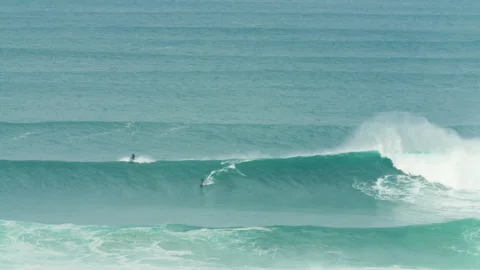 Long distance view of pro surfer surfing on ocean waves near jet ski driver 스톡 동영상 163266315