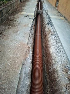 Long ditch prepared for sewerage installation in urban area with visible dr.. Stock Photos