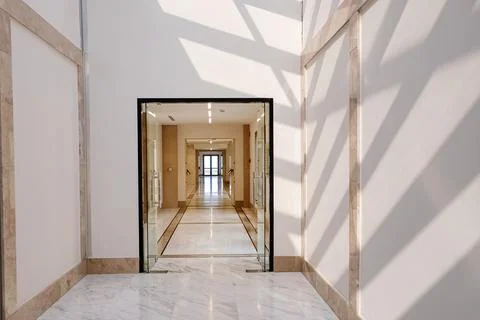 Long empty corridor in light colors with sunlight and shadows. Stock Photos