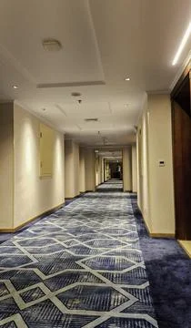 Long empty corridor of a modern hotel with blue patterned carpet Stock Photos