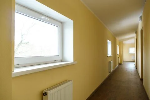 A long empty corridor in an office building. A new modern heating radiator on Stock Photos