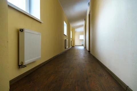 A long empty corridor in an office building. A new modern heating radiator on Stock Photos