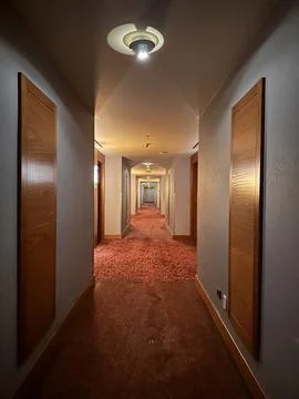 Long empty hotel corridor with warm lighting Stock Photos