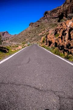 A long, empty road with a blue sky in the background Stock Photos