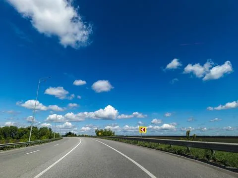 A long empty road with a blue sky and clouds in the background Stock Photos