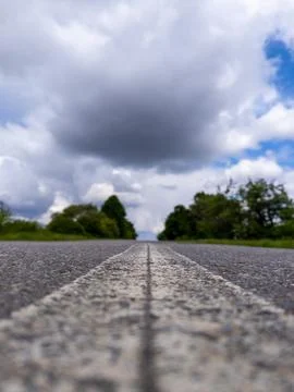 A long empty road with a cloudy sky in the background Stock Photos