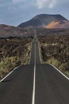 Long empty road crossing volcanic landscape in lanzarote, canary islands Foto stock