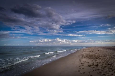Long empty sand beach on Hel peninsula in Poland with dramatic, cloudy blue sky Stock-Fotos