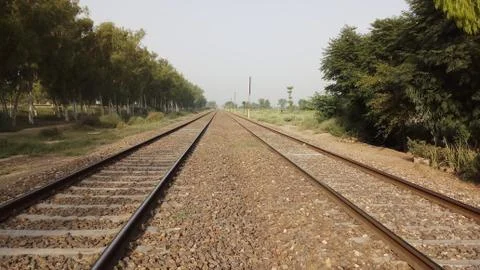Long endless double railway train track surrounded of rural landscape Stock Photos