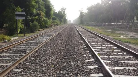 Long endless double railway train track surrounded of rural landscape Foto stock