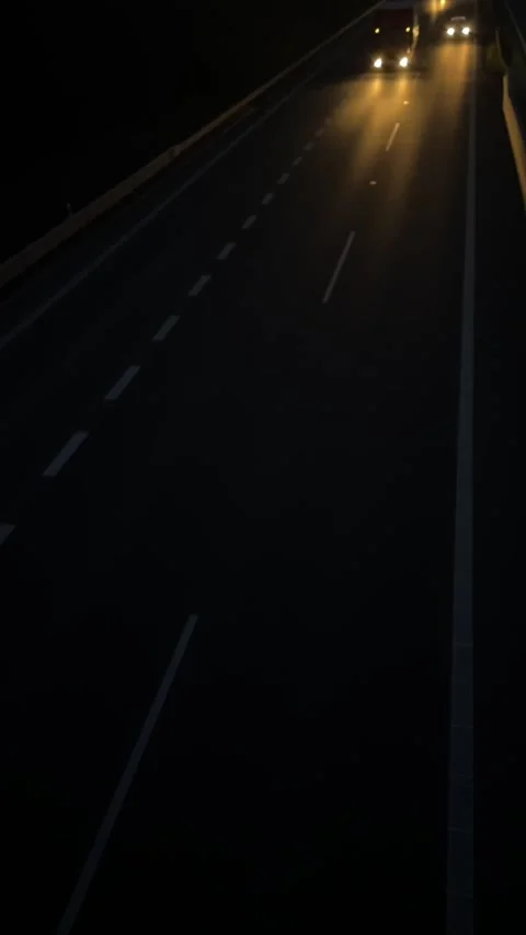 Long exposure captures passing vehicle lights on dark highway Stock Footage 335366342