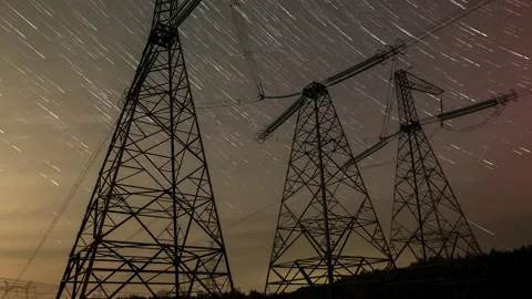 Long exposure captures star trails above power transmission towers at night Stock Footage 313486617