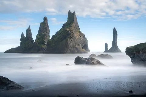 Long exposure of the coast of Vik. Fish-shaped rock formation in the sea close Stock Photos