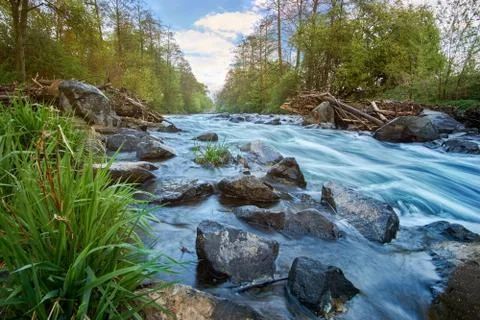 Long exposure from a floating, idyllic river with stones and grass in the Foto stock