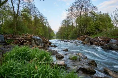 Long exposure from a floating, idyllic river with stones and grass in the Stock Photos