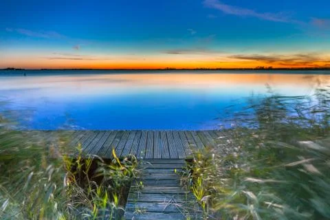 Long Exposure Image of Blue  Sunset over a Jetty on the shore of a Lake Stock Photos