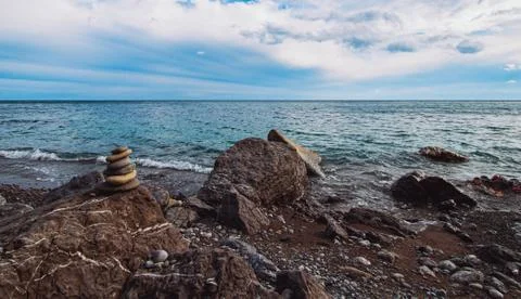 Long exposure image of Dramatic sky seascape with rock in the foreground suns Stock Photos