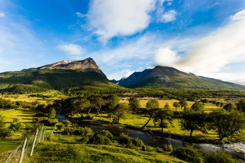 Long exposure of mountain with green fields and cloudy blue sky Stock Photos