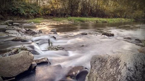 Long exposure of the mountain river in the rays of the setting sun. Stock Photos