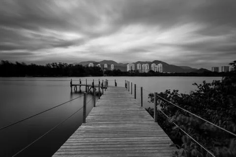 Long exposure of pier in calm lake, with nature all around, water is silky Foto stock