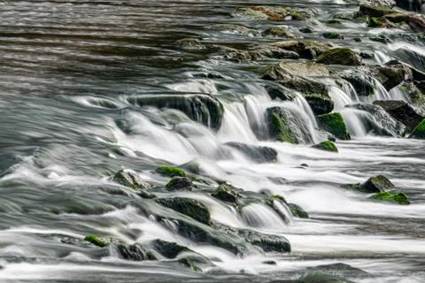 Long exposure as the River Meavy flows over rocks at Lopwell Weir, Plymouth, 库存照片