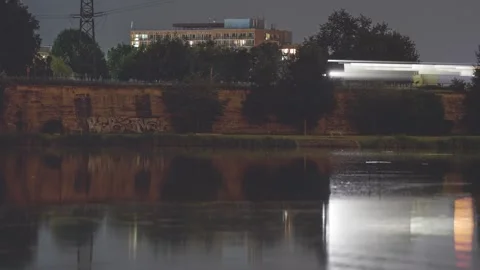 A long-exposure shot of a passing train at night, its lights streaking Stock Footage 285152224