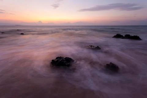 Long exposure shot of some rocks in the evening surf at Kamaole Beach in Maui Stock Photos