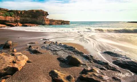 Long exposure of waves flowing over a rocky beach at Pancake Rocks, New Zealand Stock Photos