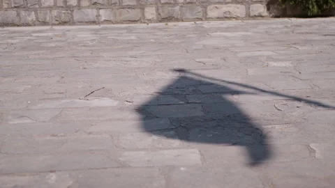 Long flag shadow cast across concrete pavement in sunlight Vídeos de archivo 329520818