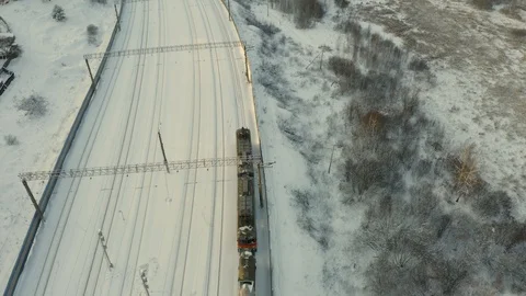Long freight train coming on the railroad station at sunset in winter. Aerial Stock Footage 126359766