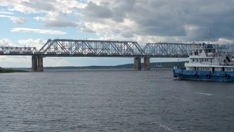 A long freight train crosses a bridge over a wide river. . Filming from a ferry Stock Footage 140859649