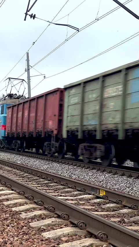 Long freight train moving along railroad tracks with multiple cargo cars Stock Footage 318651746