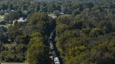Long freight train passing through dense woodland near Gentry, Arkansas Stock Footage 345343948
