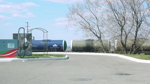 A long freight train with tanks makes movement past the refueling of cars. Video stock 108575011
