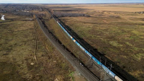 Long freight train traveling on a railway track through a vast rural landscape Stock Footage 288116621