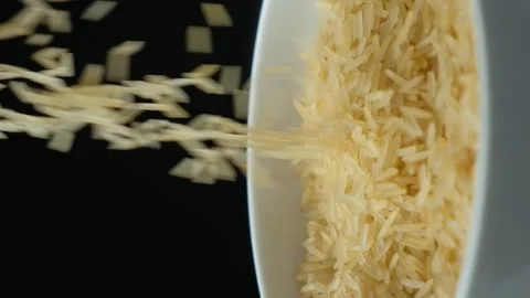 Long grain parboiled basmati rice pouring on black background, vertical slow 스톡 동영상 272216115