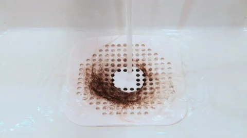 Long hair in a protective silicone grid for draining the water in the bathtub or Stock Footage 164535472